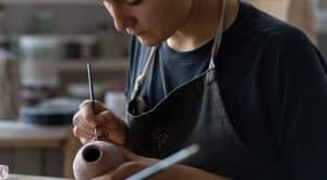 Une femme façonne une pièce de poterie avec soin, concentrée sur son travail artistique et créatif.